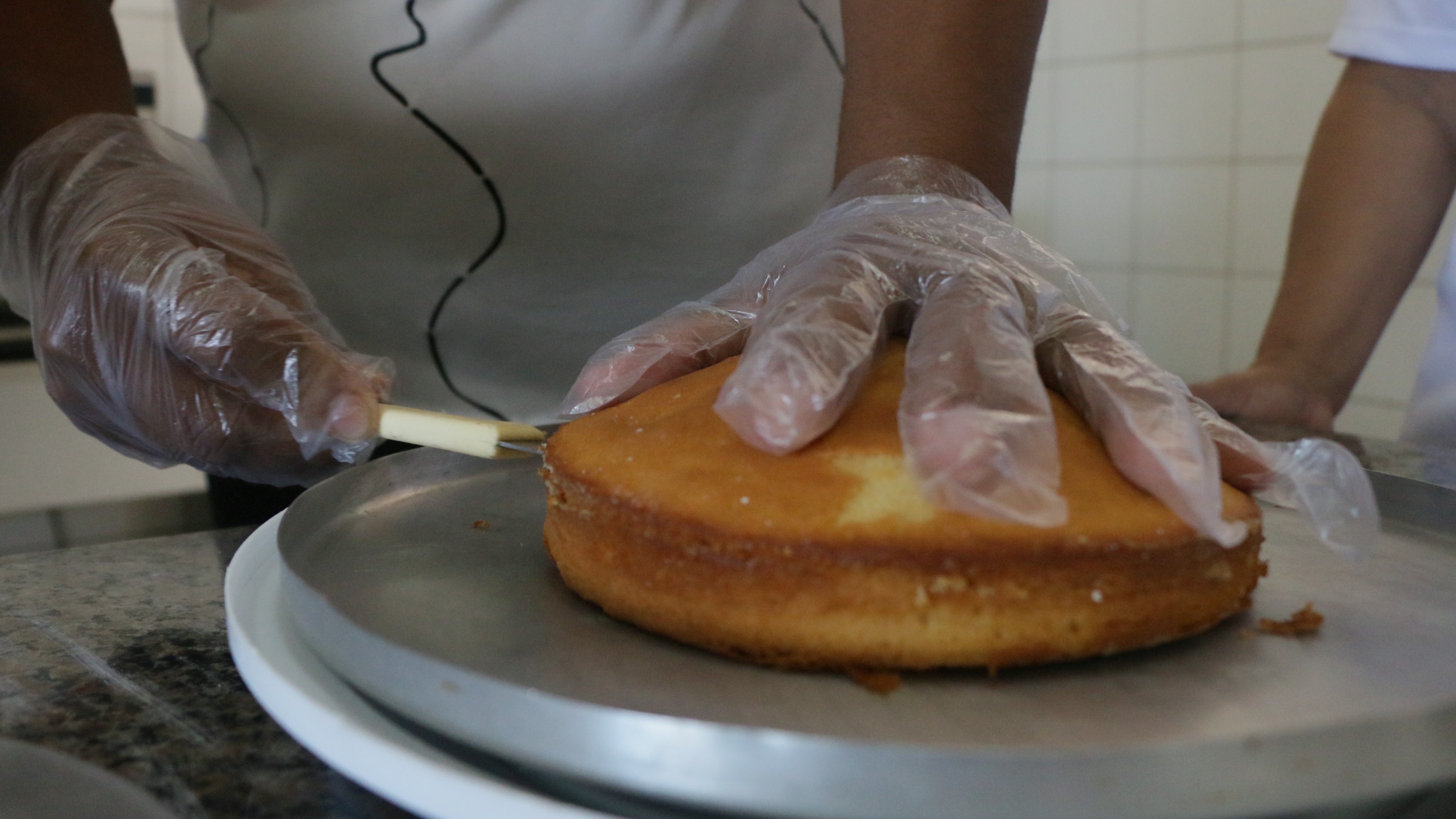 a imagem mostra duas mãos cortando um bolo fofo